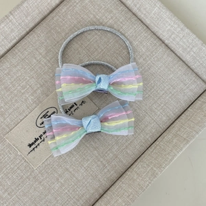 Dettaglio dei fiocchi per capelli in organza blu con strisce colorate ed elastico argento