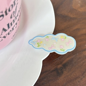 Detailansicht der Haarspange in Wolkenform mit Tulpenmuster und rosa Schleife auf Teller