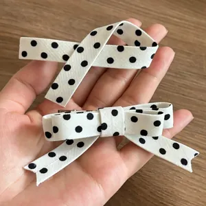 Close-up of black and white polka dot ribbon bow hair clips with metal crocodile clips