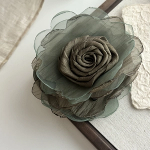 Close-up of handmade olive green mesh flower hair clip with layered chiffon petals