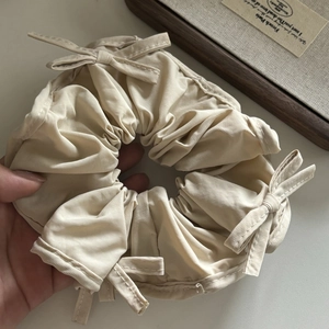 Close-up of beige satin scrunchie with bows and elegant French vintage texture