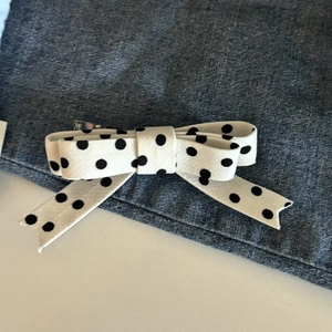 Close-up of fabric bow hair clip with black polka dots on white background with metal clip