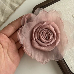 Detail of a handmade pink mesh silk rose clip held in hand to show size and texture