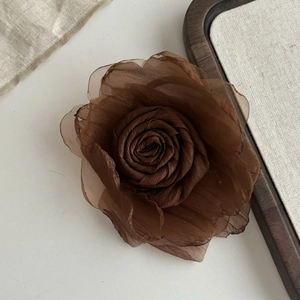 Detailed close-up of brown rose hair clip featuring layered mesh fabric and gauze petals