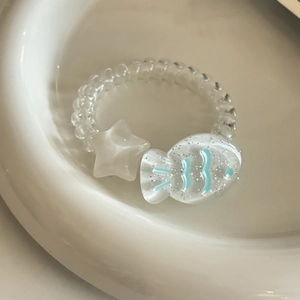 Spiralhaargummi mit mattem Stern und glitzerndem Fisch-Anhänger auf einem Keramikteller