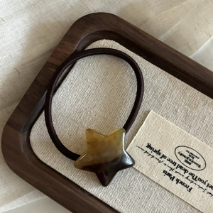 Détail de l'élastique à cheveux étoile ambrée avec cordelette marron sur bois