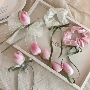 Détail de pinces à cheveux tulipes et chouchous en organza dans un plateau en bois