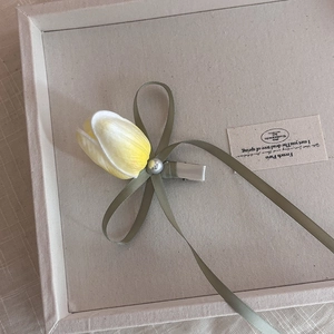 Détail de la pince à cheveux tulipe avec fleur jaune, nœud vert et perle nacrée