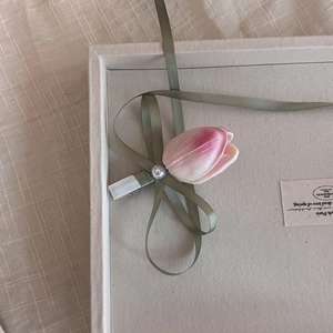 Pince à cheveux tulipe rose avec ruban vert olive et perle sur fond en lin beige