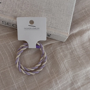 Detailed macro view of purple and beige twisted elastic hair ties on a fashion jewelry card