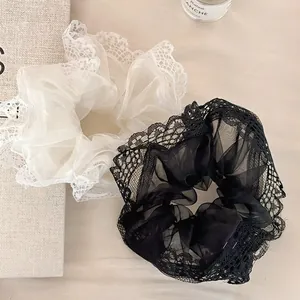 Dettaglio di elastici per capelli in pizzo e organza bianco e nero con texture a rete