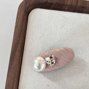 Detail einer rosafarbenen Glitzer-Haarspange mit großer Perle und Herz-Kristall