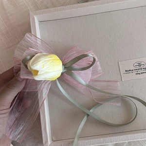 Détail de la barrette en organza rose avec tulipe artificielle et ruban de soie vert