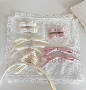 Detailed flat lay of cream and pink satin bow hair clips with pearls on lace