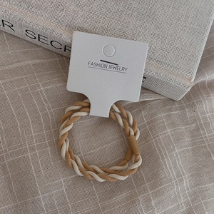 Cream color high-elasticity braided hair tie with twisted design on fabric background