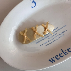 Detailed view of three cream satin bows on a fabric wrapped hair clip in a ceramic tray