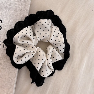 Elegant black lace and white polka dot bow scrunchie on light wood table