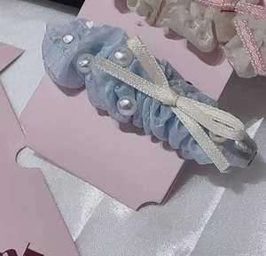 Detailed view of light blue lace hair clip with white pearls and cream ribbon bow
