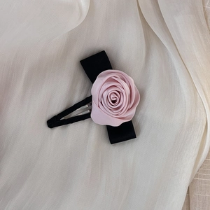Elegante clip para el pelo con rosa de tela rosa y cinta negra sobre gasa crema