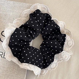 Detailed shot of black polka dot scrunchie with white floral embroidery lace trim