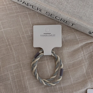 Macro shot of two-tone braided spiral hair tie in grey and cream on a display card