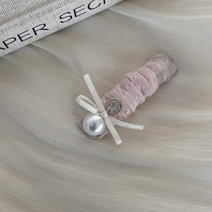 Detail of pink mesh fabric hair clip with ribbon bow, pearl, and vintage metal button