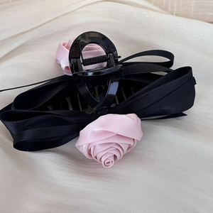 Detalle de la pinza para el cabello con lazo negro y rosas de satén rosa en tela
