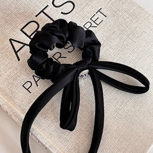 Detail of black satin bow scrunchie with sparkling rhinestone center on vintage book