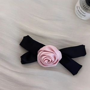 Detalle de la elegante rosa de satén rosa y lazo negro sobre tela con textura suave