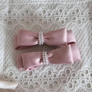 Pink satin bow hair clips with double row pearl beads on floral lace background