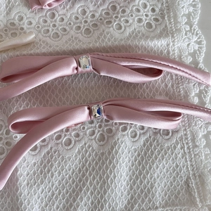 Elegant pair of pink satin bow hair clips with central crystal on white floral lace