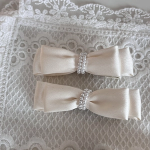 Close-up of cream satin bow hair clips with elegant double-row pearl detailing set of two