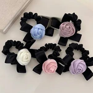 Détail de cinq chouchous roses en satin avec nœuds noirs aux couleurs pastel variées