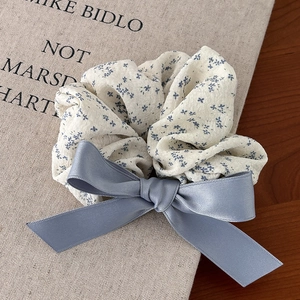Chouchou fleuri bleu élégant avec nœud en satin pour coiffure femme sur un livre vintage