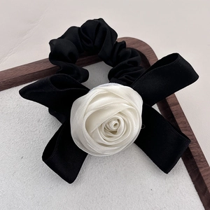 Chouchou élégant avec rose blanche en tissu et nœud en satin noir sur plateau bois