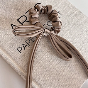 Detail of satin bow hair tie with champagne gold fabric and teardrop crystal accent