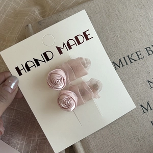 Detailed view of handmade pink silk rose hair clips with delicate mesh on display card