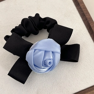 Vue détaillée d'un grand chouchou noir avec une rose en satin bleu clair en relief