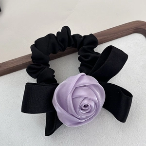 Gros plan d'un chouchou avec une rose en soie et un nœud en ruban noir pour les cheveux