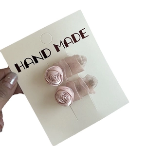 Pair of handmade pink fabric rose hair clips with delicate mesh on display card