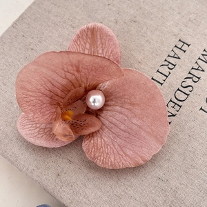 Close-up of pink orchid flower hair clip with pearl center on linen book cover