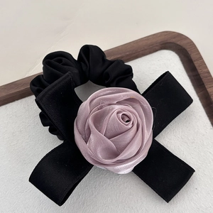 Gros plan d'un chouchou rose en satin avec un nœud noir et un élastique à cheveux