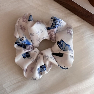 Détail d'un chouchou en satin avec papillons bleus et calligraphie chinoise élégante