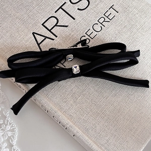 Close-up of black satin ribbon hair clips with a rectangular crystal on a vintage book