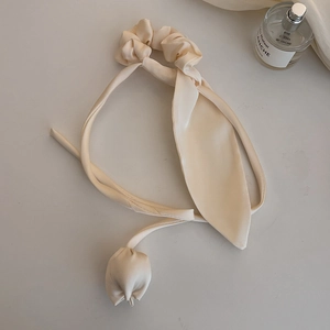 Dettaglio dell'elegante elastico per capelli in raso crema con ciondolo a tulipano e nastri