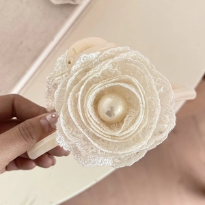 Close-up of elegant white lace floral hair clip with a large central pearl bead detail