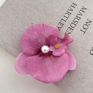 Silk pink orchid flower hair clip with pearl center on rustic linen background