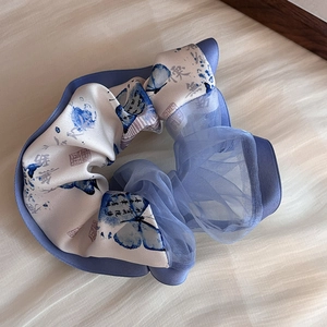Vue détaillée du motif papillon et de la calligraphie sur chouchou en satin
