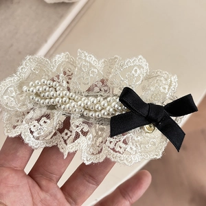 Detail of sweet white lace hair clip with pearls and elegant black ribbon bow