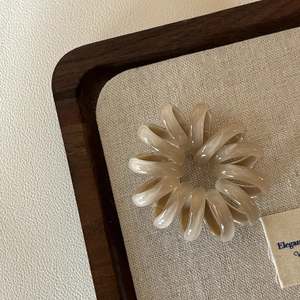 Nahaufnahme der Spirale Telefonkabel Haargummi in elegantem Beige auf Textiltablett